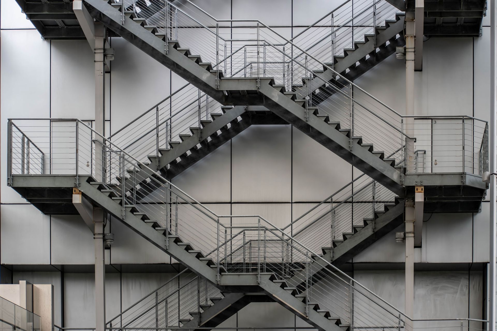 Crossing metal staircases on an industrial building facade in Tokyo, Japan.