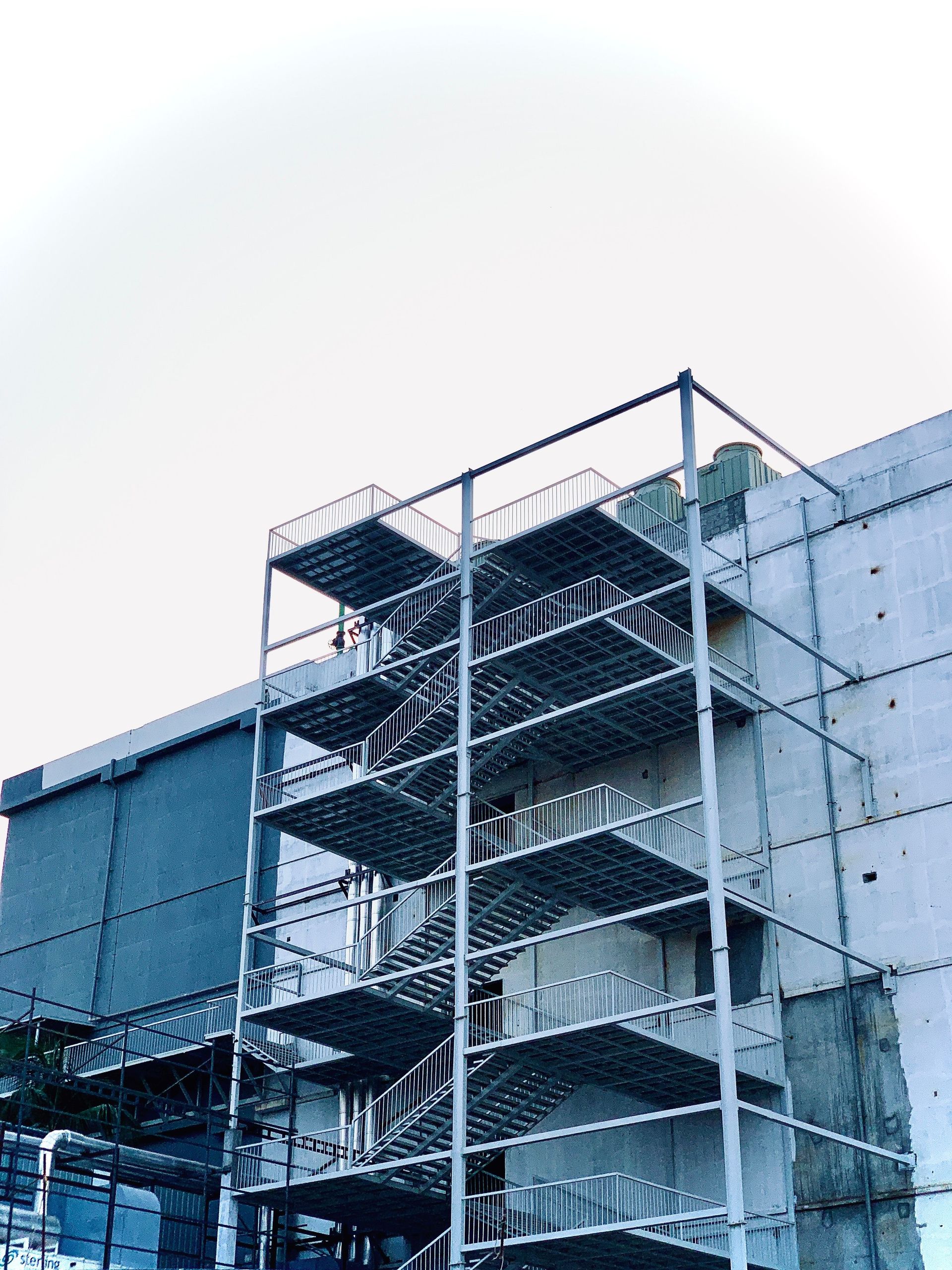 A contemporary building featuring an external metal staircase in an urban setting.