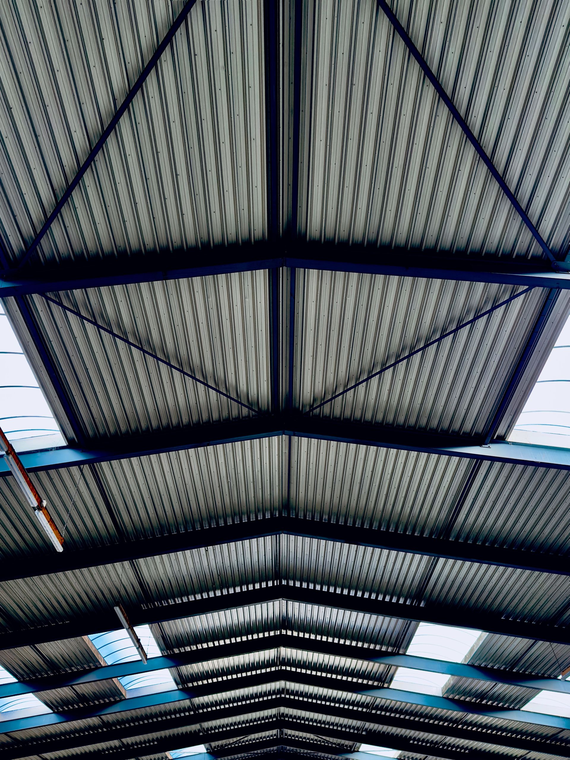 High-angle view of a modern industrial roof with corrugated steel and beams.