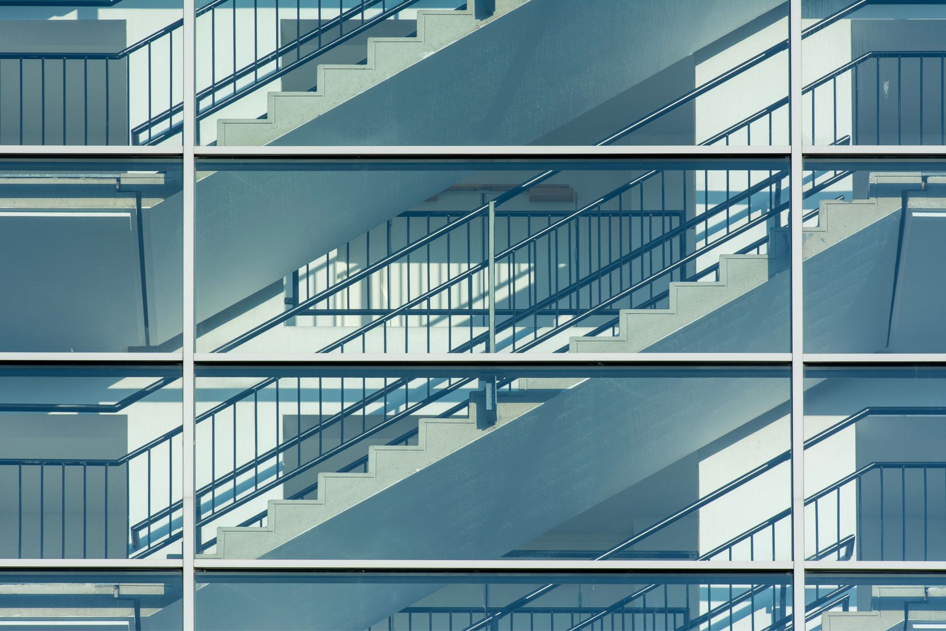 Symmetrical view of a modern building's glass facade reflecting interior staircases.